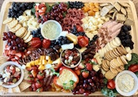 a tray full of cheese, crackers, fruits, and crackers