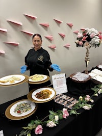 a woman standing in front of a table with plates of food