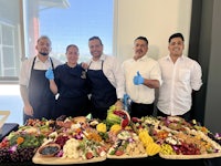 a group of people posing in front of a large platter of food